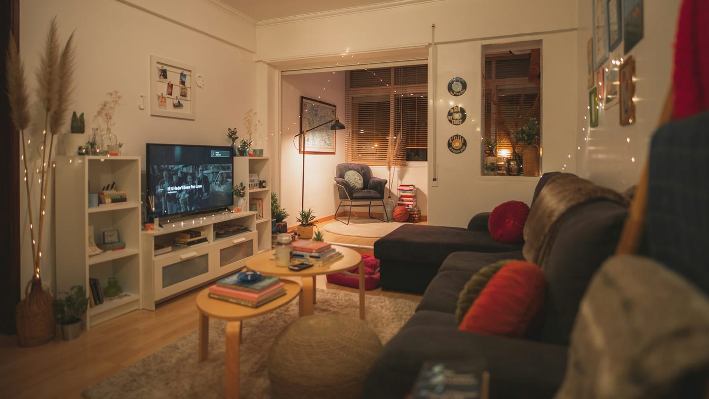 A small open-plan living area with a sofa used as a zone divider between the living space and a small dining table behind it