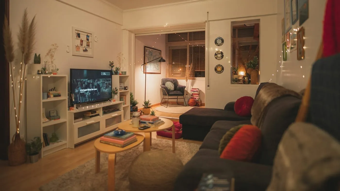 A small open-plan living area with a sofa used as a zone divider between the living space and a small dining table behind it