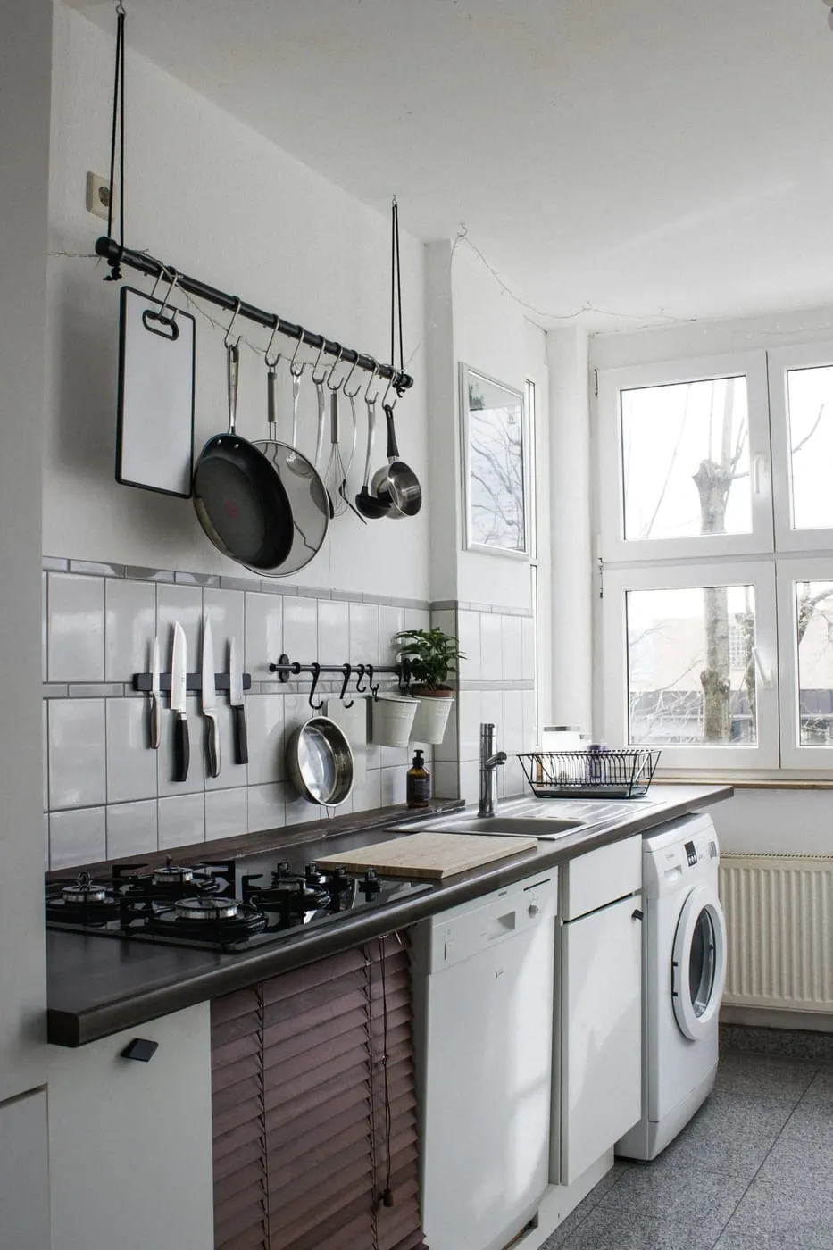 A small apartment bathroom organized vertically with over-toilet shelf and clear surfaces