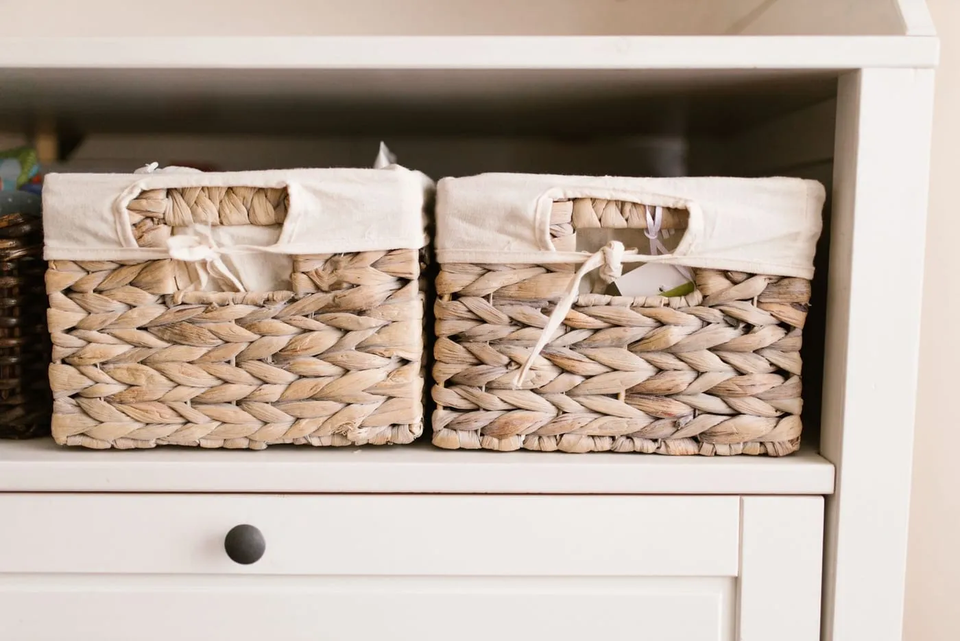 Woven storage baskets styled on a small apartment shelf alongside books and a plant