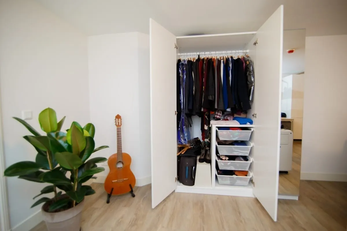A closet with open sliding doors showing folded gear stored on a shelf, an example of hiding home gym equipment out of sight