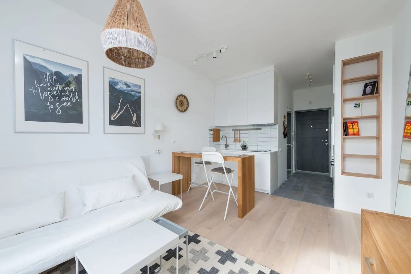 A bright studio with the bed zoned into a back corner and a sofa facing the living area
